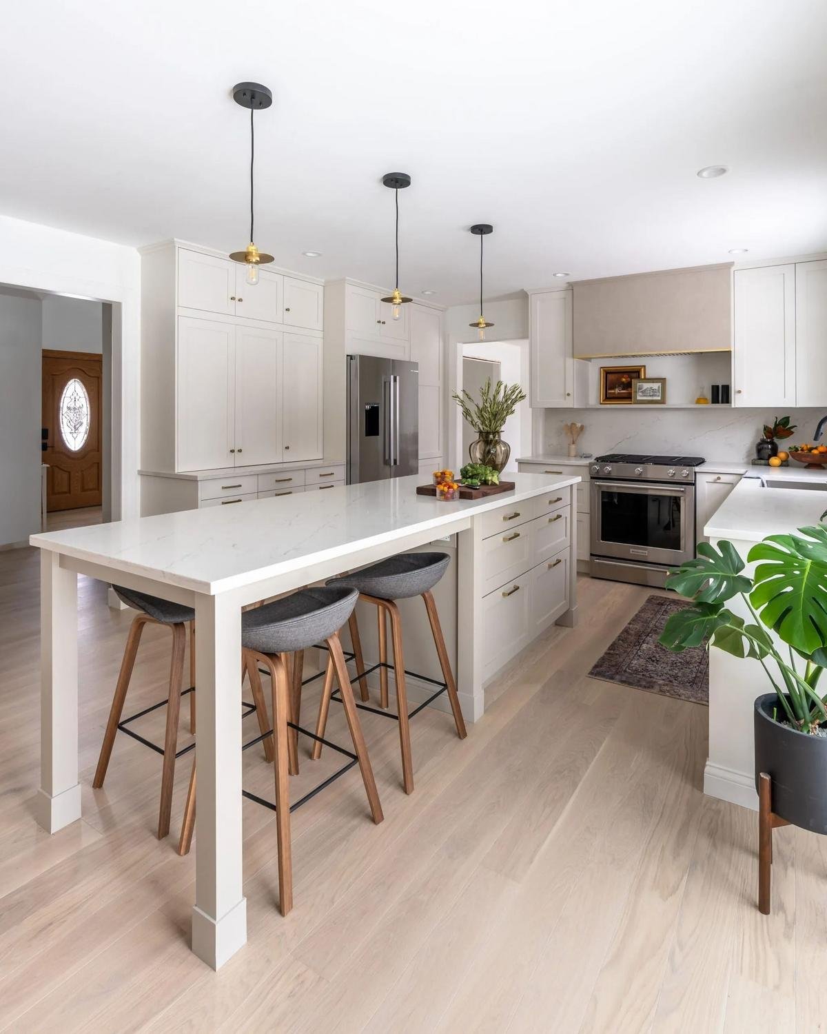 Renovated kitchen with floor-to-ceiling white cabinets, marble island, and brass pendant lights
